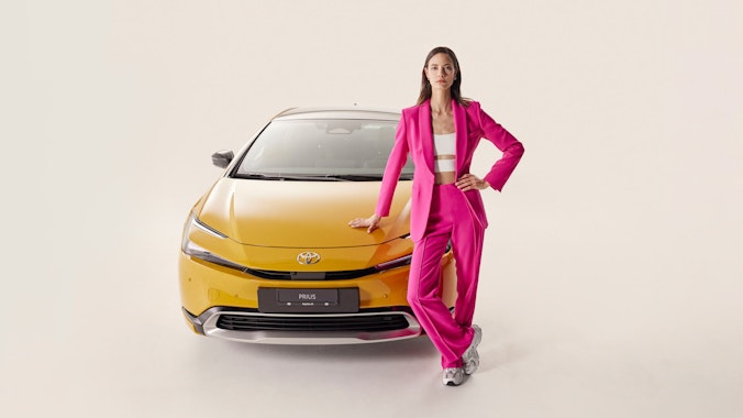 Une femme se tient devant une Toyota Prius jaune