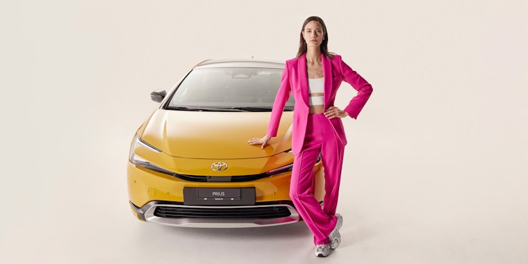 Frau steht vor einem gelben Toyota Prius
